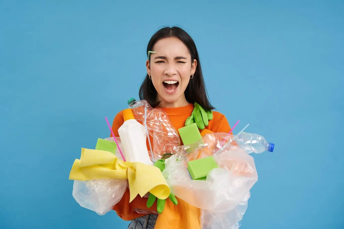 Шокированный экоактивист собирает много пластика для переработки, с огорчением глядя на бутылки и несортированный мусор.